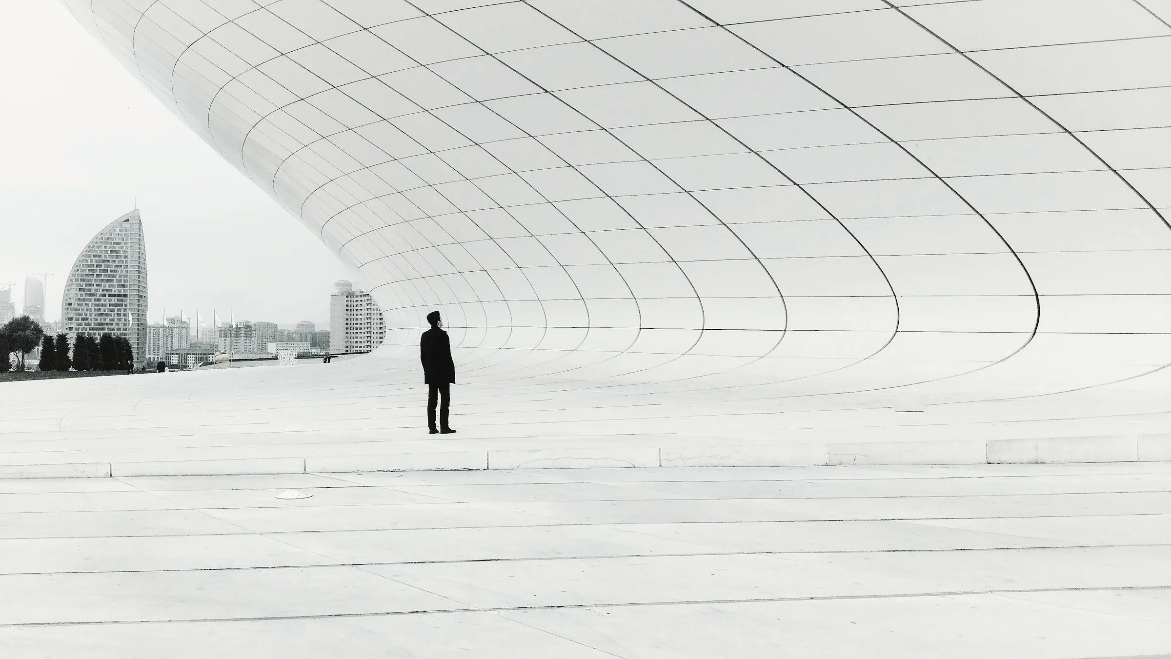 Una persona pequeña ante una gran arquitectura blanca y curva